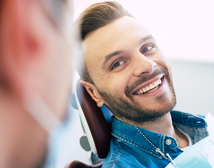 Man smiling in dental chair during exam, representing comfortable dental visit and positive patient experience