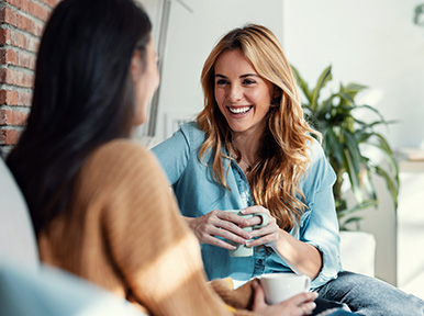 Two women smiling and talking indoors, representing friendly dental team and comfortable patient experience