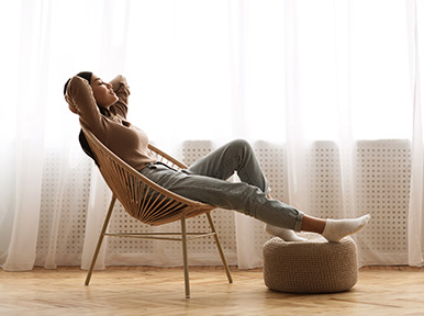 Woman relaxing in chair at home, representing comfortable, stress-free dental care experience