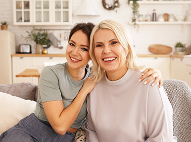 Mother and daughter smiling together at home, representing family dentistry and healthy smiles for all ages